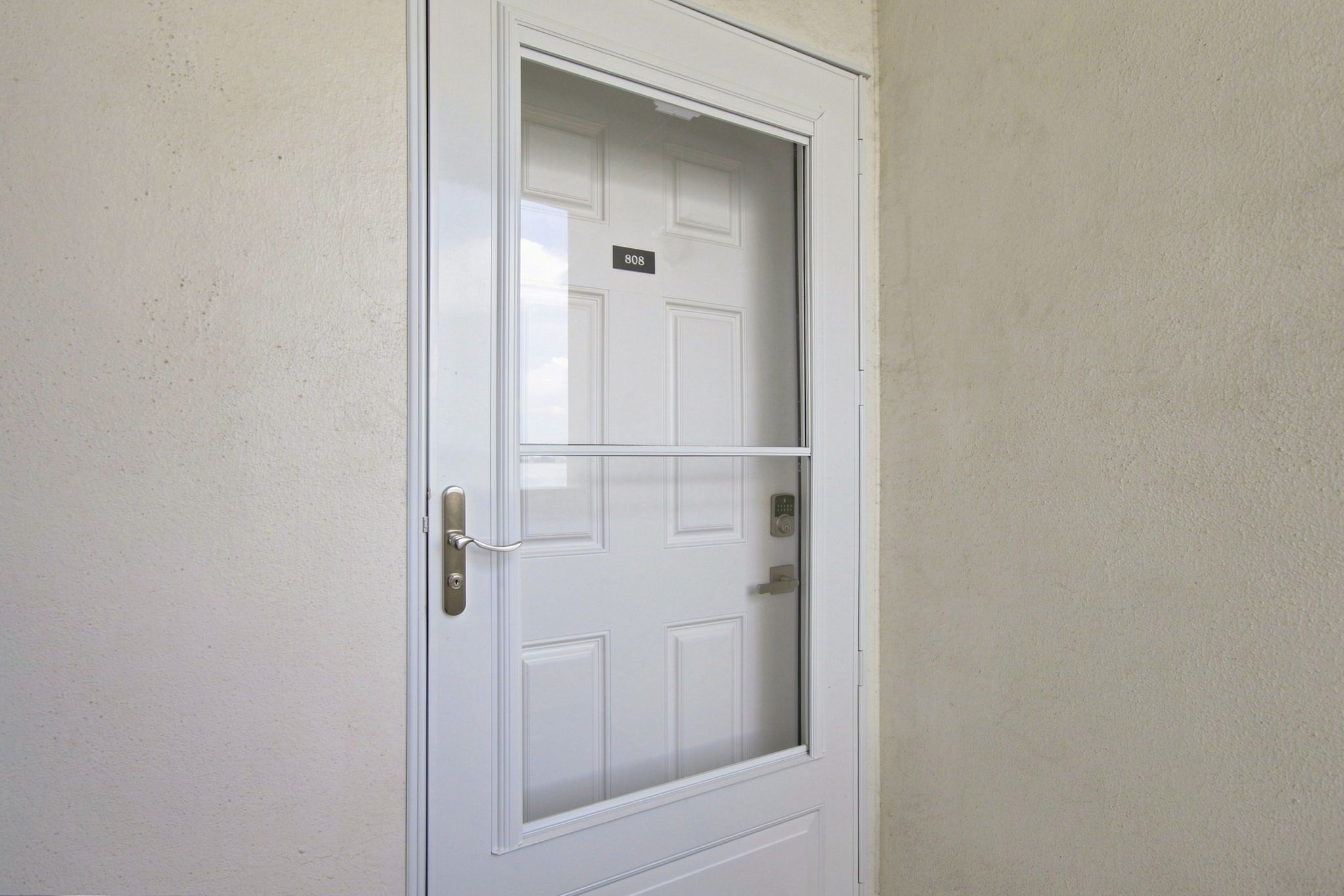 A white door with a number plate '808' and a security keypad.