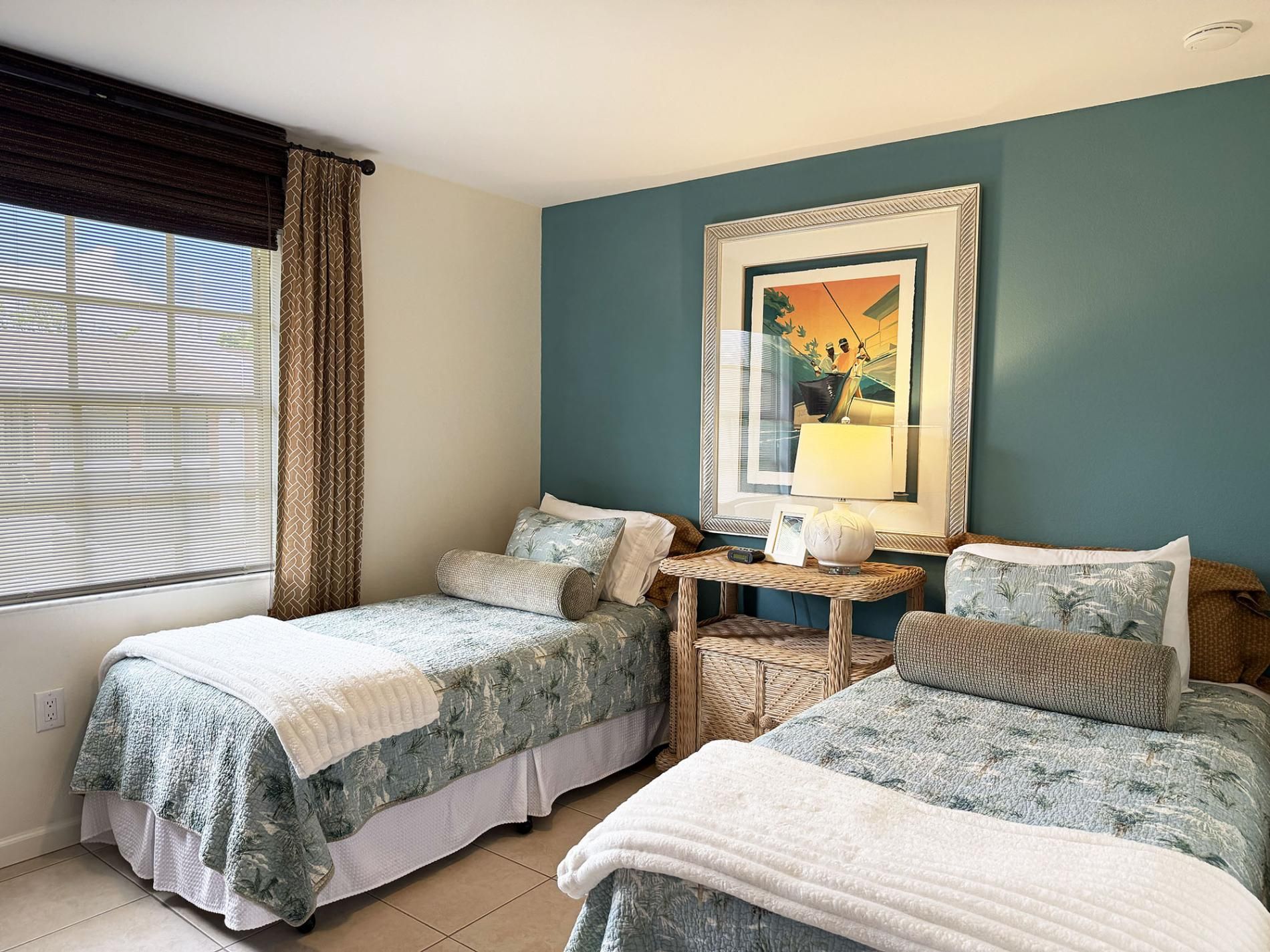 Een hotelkamer met twee bedden, een tafeltje, een stoel en een raam met zonwering.