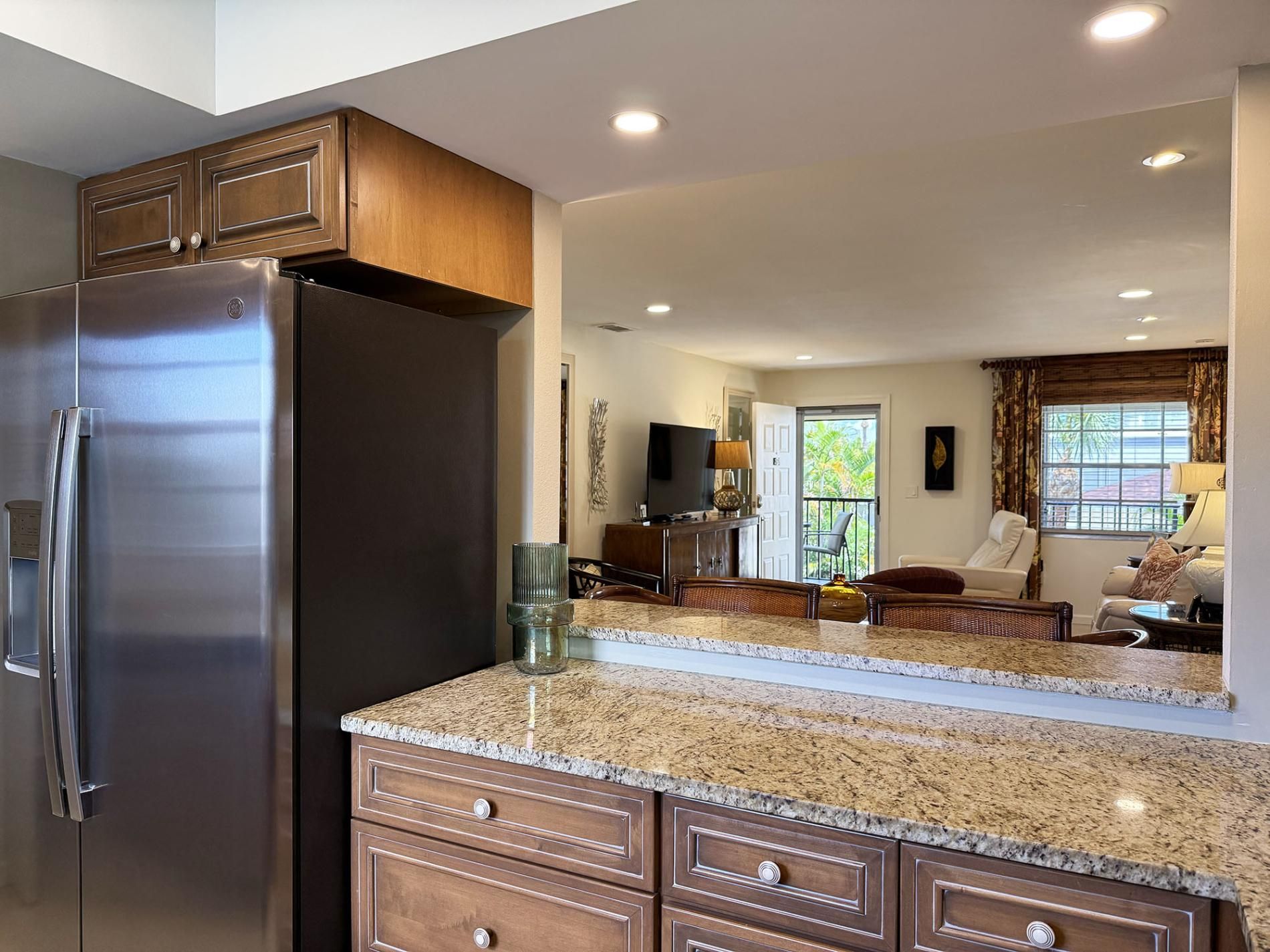 Una cocina moderna con refrigerador de acero inoxidable, encimera de granito y muebles de madera.