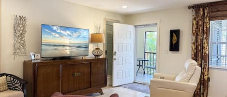 A living room with a television, a sofa, a chair, and a decorative wall piece.