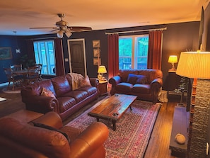 A living room with a brown leather sofa, a matching armchair, a coffee table, and a patterned rug.