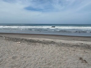 En strand med en sandstrand och vågor som slår in mot land.