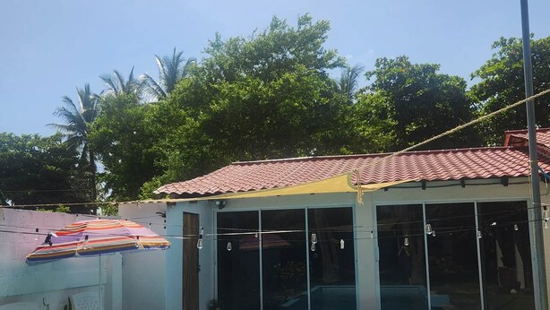 Piscina com deck revestido, área coberta com janelas e céu claro.