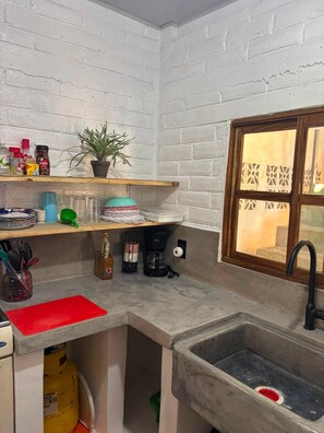A compact kitchen with a built-in sink, a coffee maker, and a window with decorative glass. - Wonderful 2-bedroom beachhouse with AC in pleasant La Libertad (la libertad)