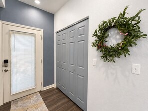 A hallway with a door, a grey door, and a wall-mounted wreath. - Emerald Escape | Lake Views (Lake Ozark)