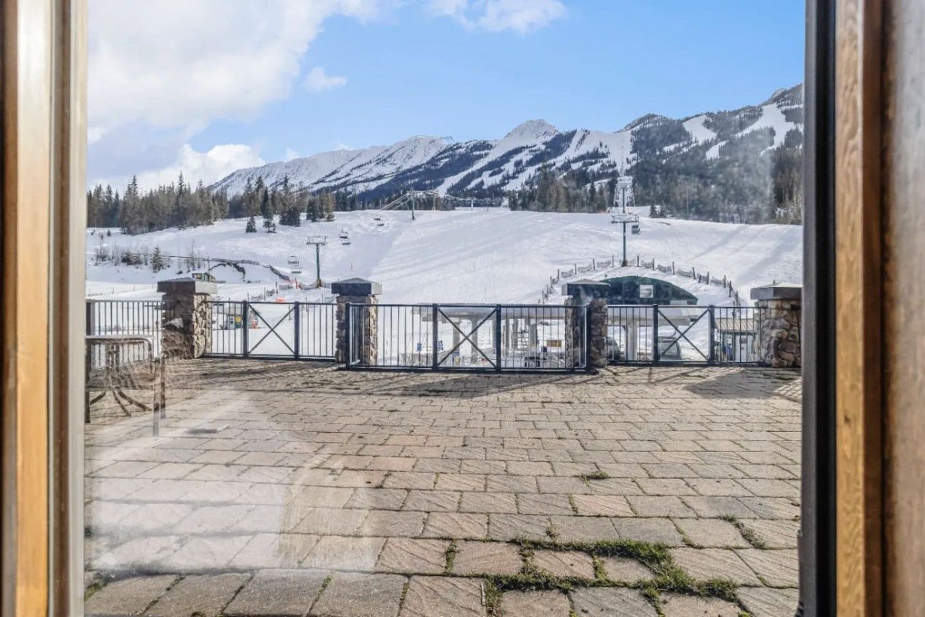 Un área pavimentada con una reja de metal, montañas nevadas y un cielo despejado.