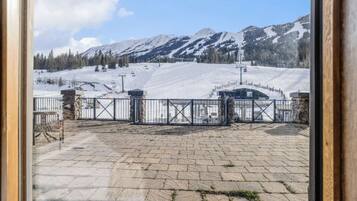 Un área pavimentada con una reja de metal, montañas nevadas y un cielo despejado.