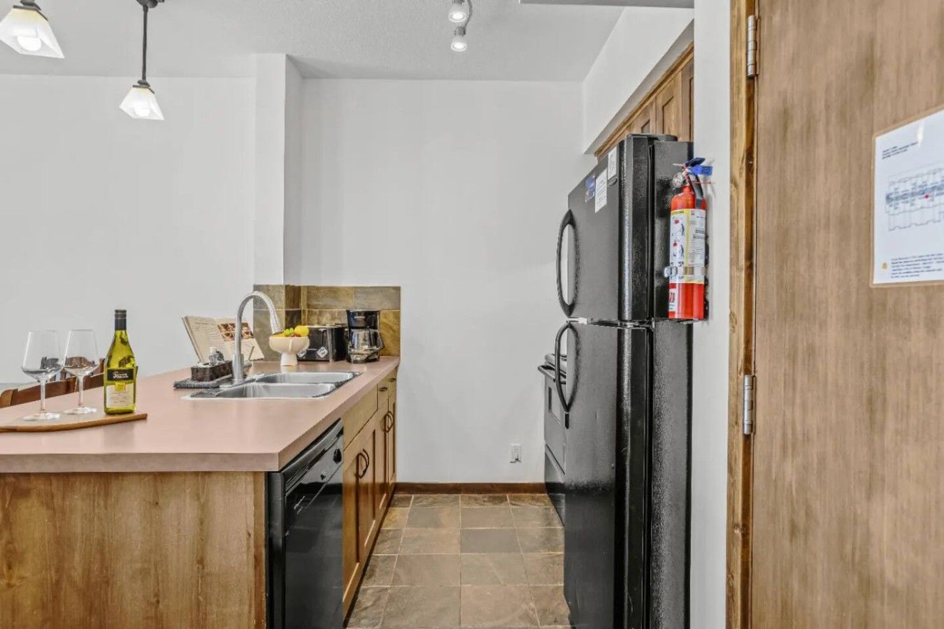 Une cuisine moderne avec un îlot central, un réfrigérateur noir et un meuble en bois.