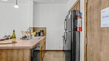 Une cuisine moderne avec un îlot central, un réfrigérateur noir et un meuble en bois.