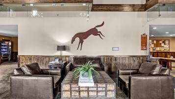 Un hall d’entrée avec des canapés en cuir, une table basse en bois et une silhouette de cheval fixée au mur.