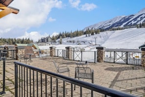 Een terras met zitplaatsen buiten en uitzicht op een besneeerd berglandschap.