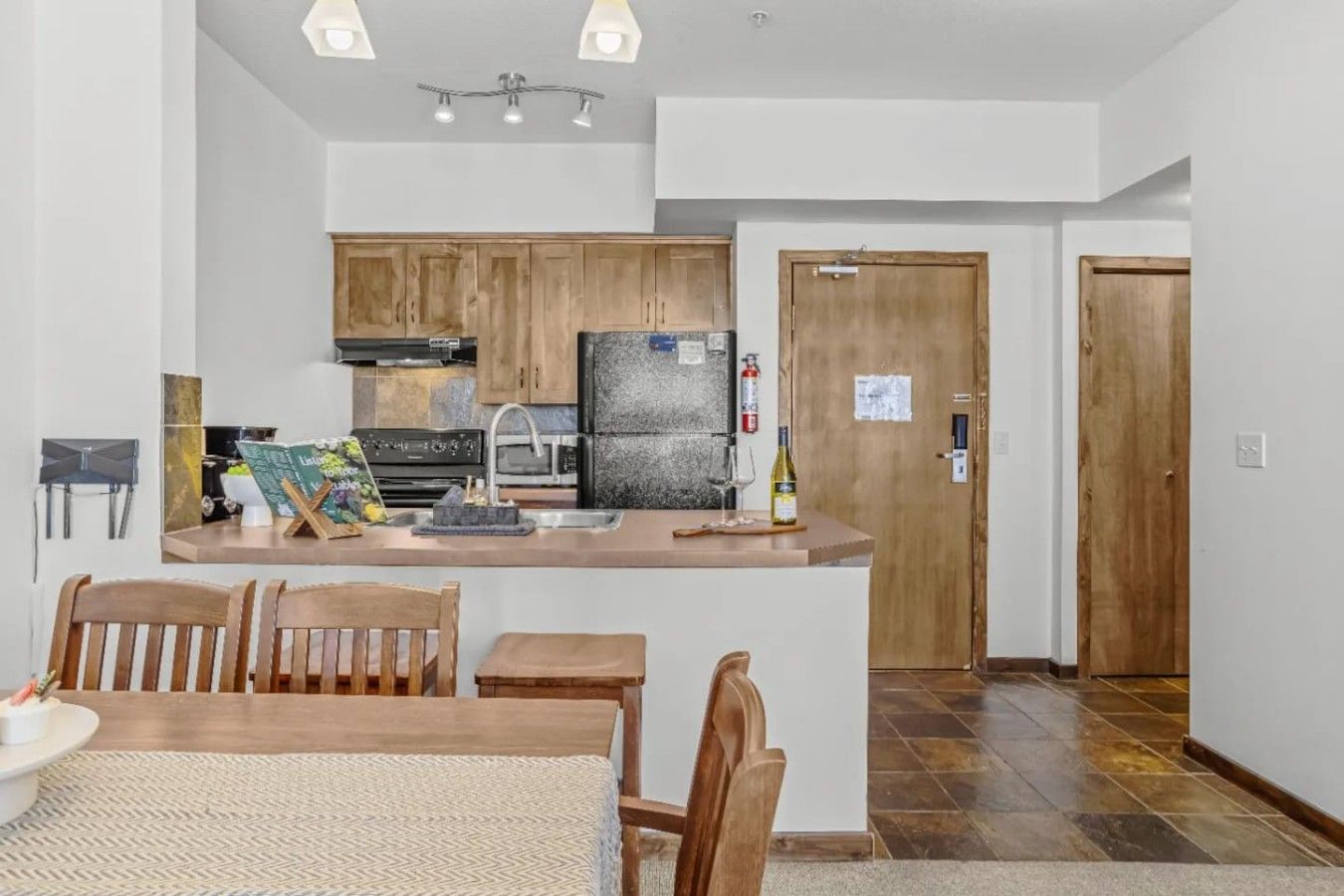 A modern kitchen with wooden cabinets, a central island, and a dining area with a table and chairs.
