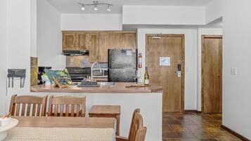 A modern kitchen with wooden cabinets, a central island, and a dining area with a table and chairs.