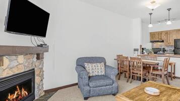 A living room with a fireplace, a television mounted on the wall, and a dining area with wooden furniture.