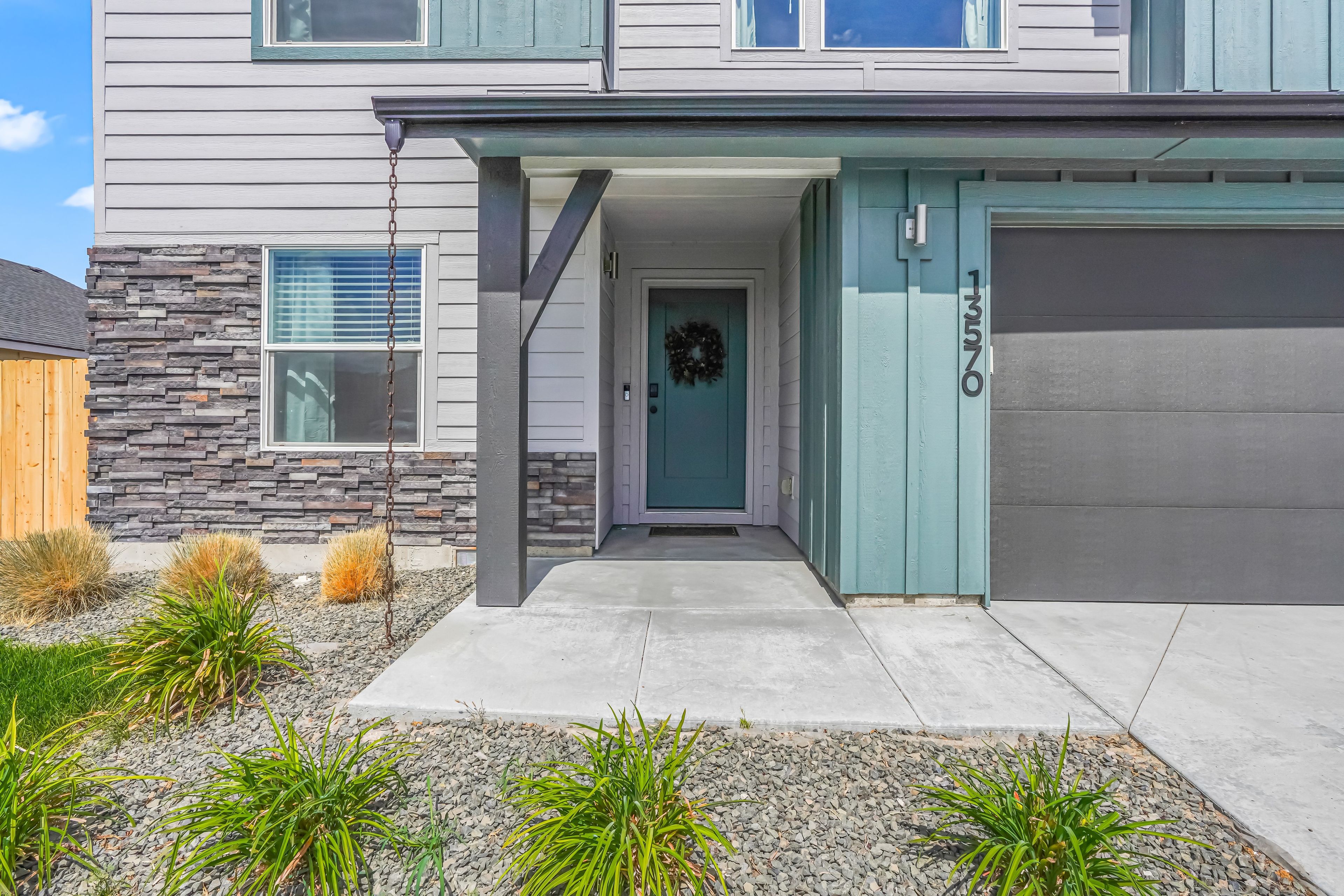 A modern two-story house with a stone facade, a front porch, and a garage.