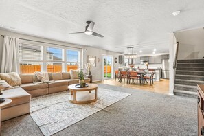 Uma sala de estar ampla com sofá, mesa de centro e uma área de jantar com cadeiras e mesa.