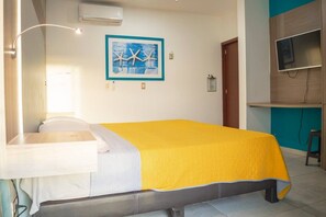 Une chambre d’hôtel avec un lit, un bureau, une chaise, une télévision et un tableau au mur.