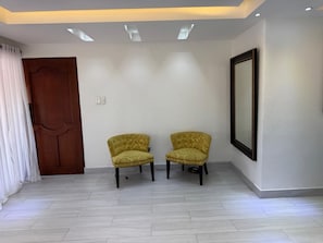 A room with two armchairs, a wooden door, and a framed picture on the wall. - Carolina Apartment (Los colonos)