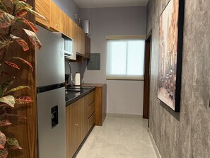 A kitchen with wooden cabinets, a stainless steel refrigerator, a built-in oven, and a window with blinds. - Loft con alberca en rooftop · Mazatlán by GPS (Mazatlán)