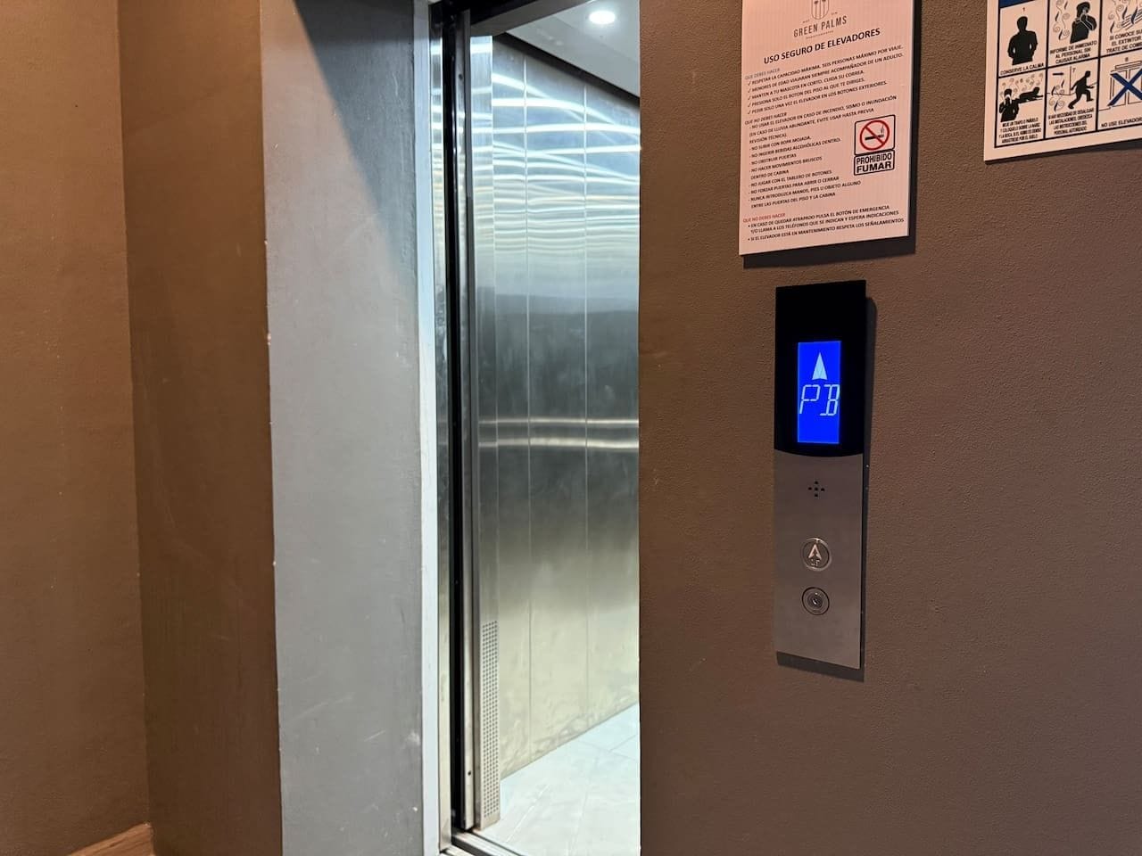 Das Innere einer Aufzugskabine mit einem digitalen Display, das 'P B' anzeigt, und einem an der Wand befestigten Schild mit Sicherheitshinweisen.