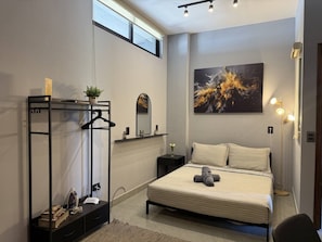 A modern bedroom with a bed, bedside table, and a large abstract painting.
