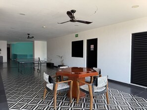 Ein Konferenzraum mit einem runden Tisch und Stühlen, einem Deckenventilator und einem fußbodenmuster.