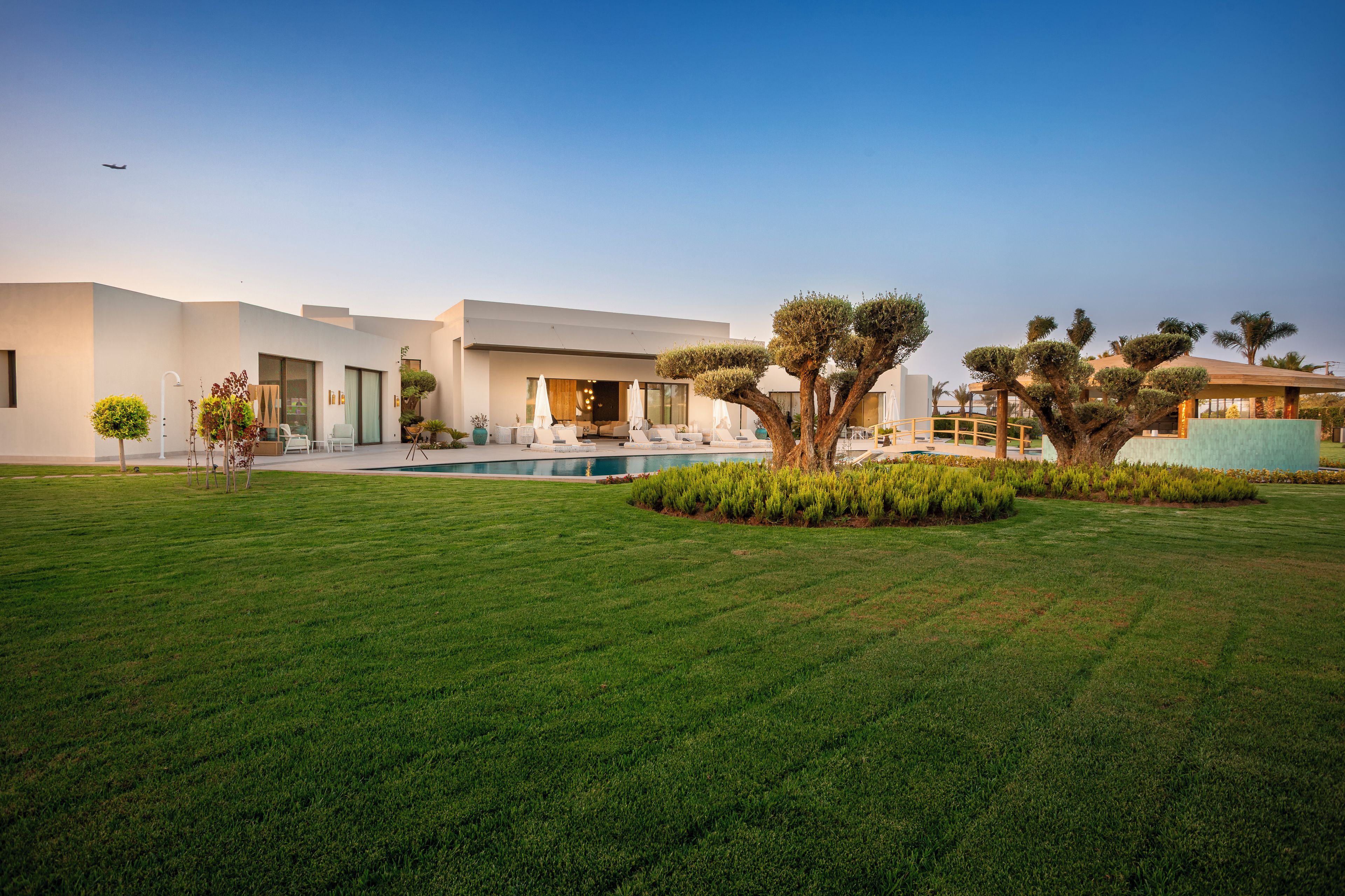 A modern house with a swimming pool, outdoor seating, and well-maintained landscaping.