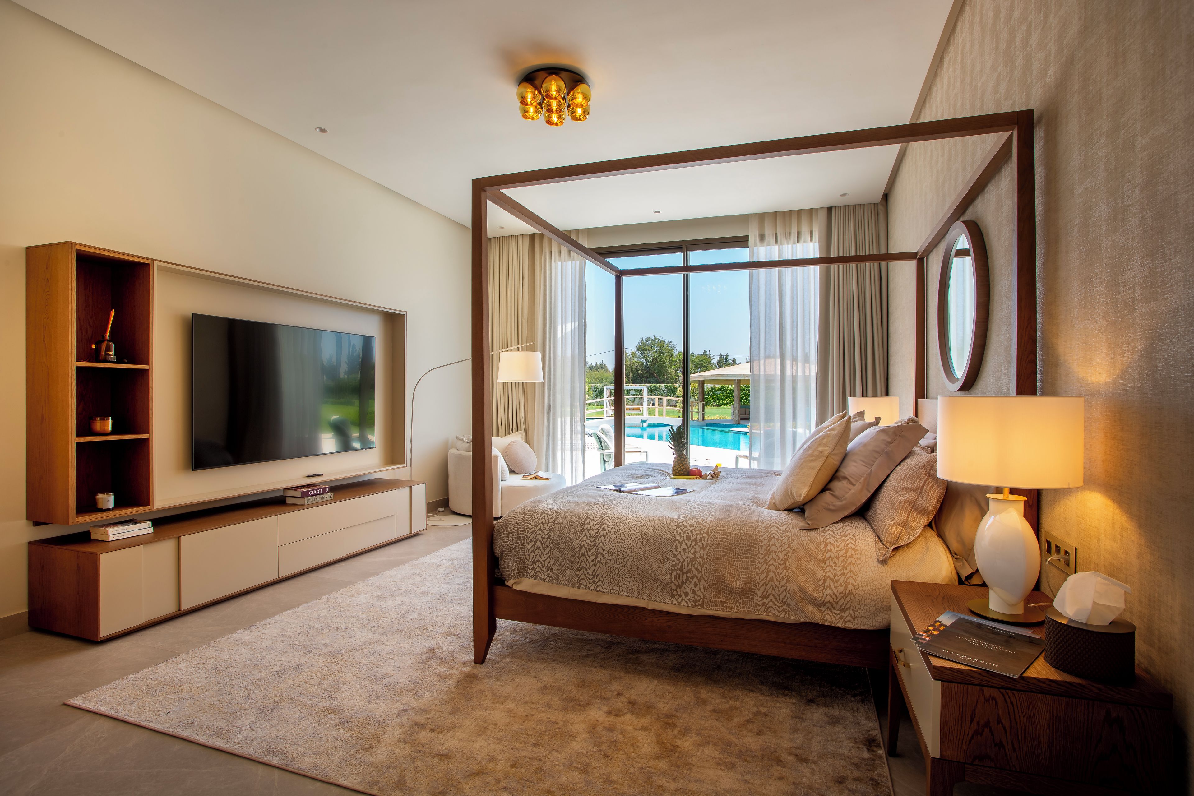 A spacious bedroom with a large bed, a television, and a view of a pool.