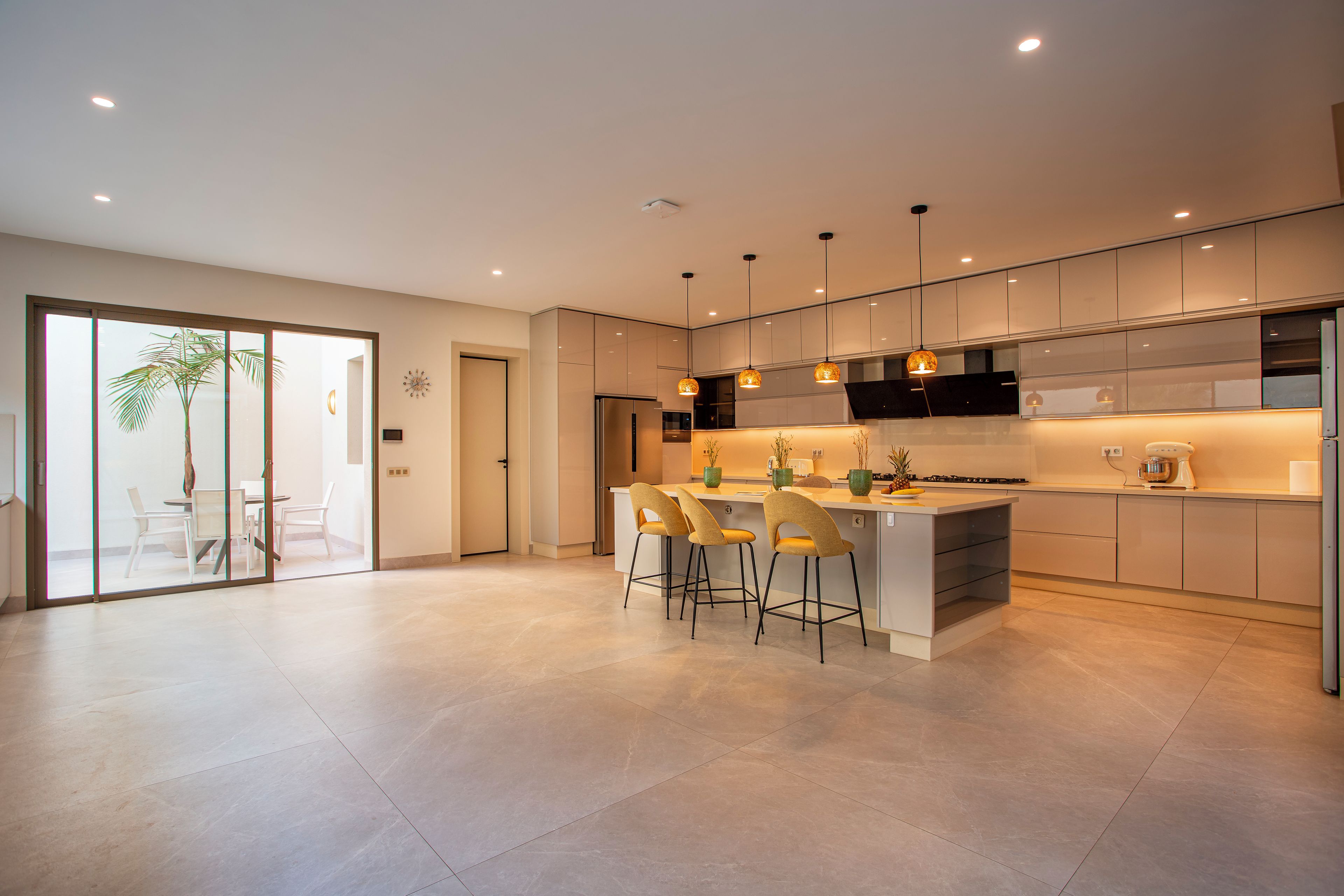 A modern kitchen with a central island, bar stools, pendant lighting, and a view into the dining area.