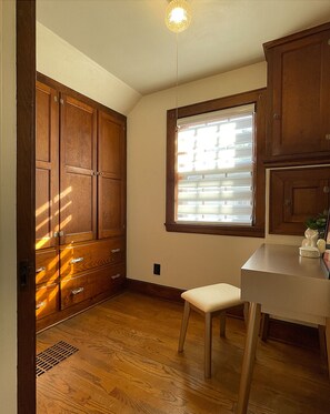 Ein Zimmer mit Holzausstattung, einem Fenster mit Jalousien, einem Sessel und einem Tisch.