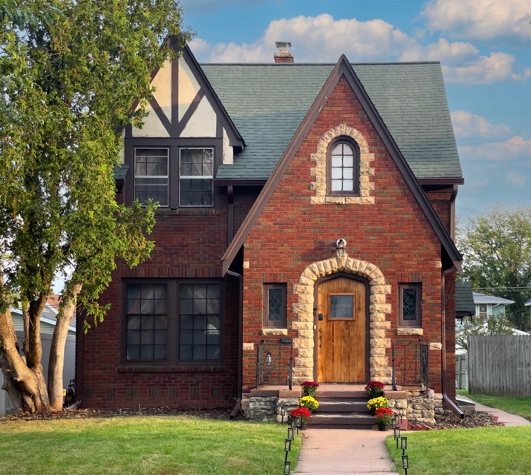 A two-story house with a prominent front entrance, large windows, and a stone archway.