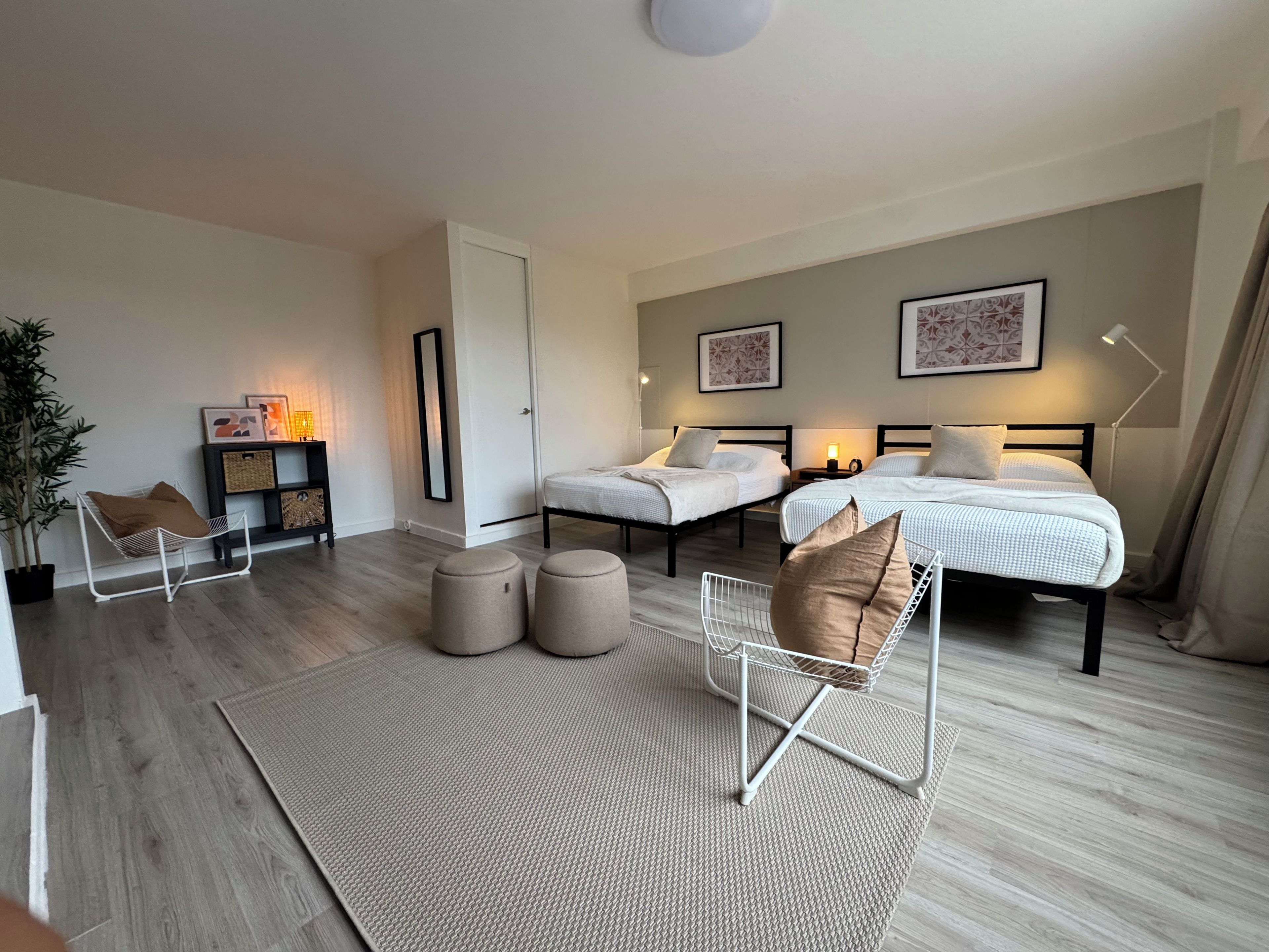 Een moderne slaapkamer met twee bedden, een zithoek en een nachtkastje.