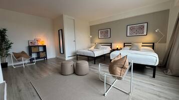 Een moderne slaapkamer met twee bedden, een zithoek en een nachtkastje.