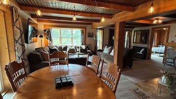 Ein gemütliches Wohnzimmer mit Esstisch aus Holz, Sofas und einem Kamin.