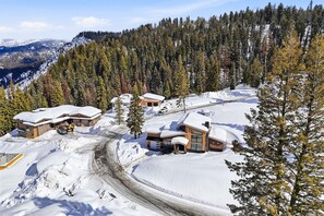 Zona de muntanya coberta de neu amb diversos edificis, incloent una cabana i un teleàsic.