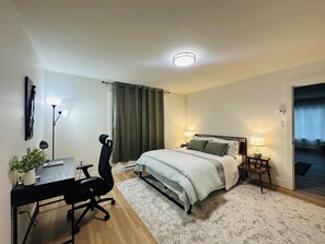 A hotel room with a bed, desk, chair, and two bedside lamps.