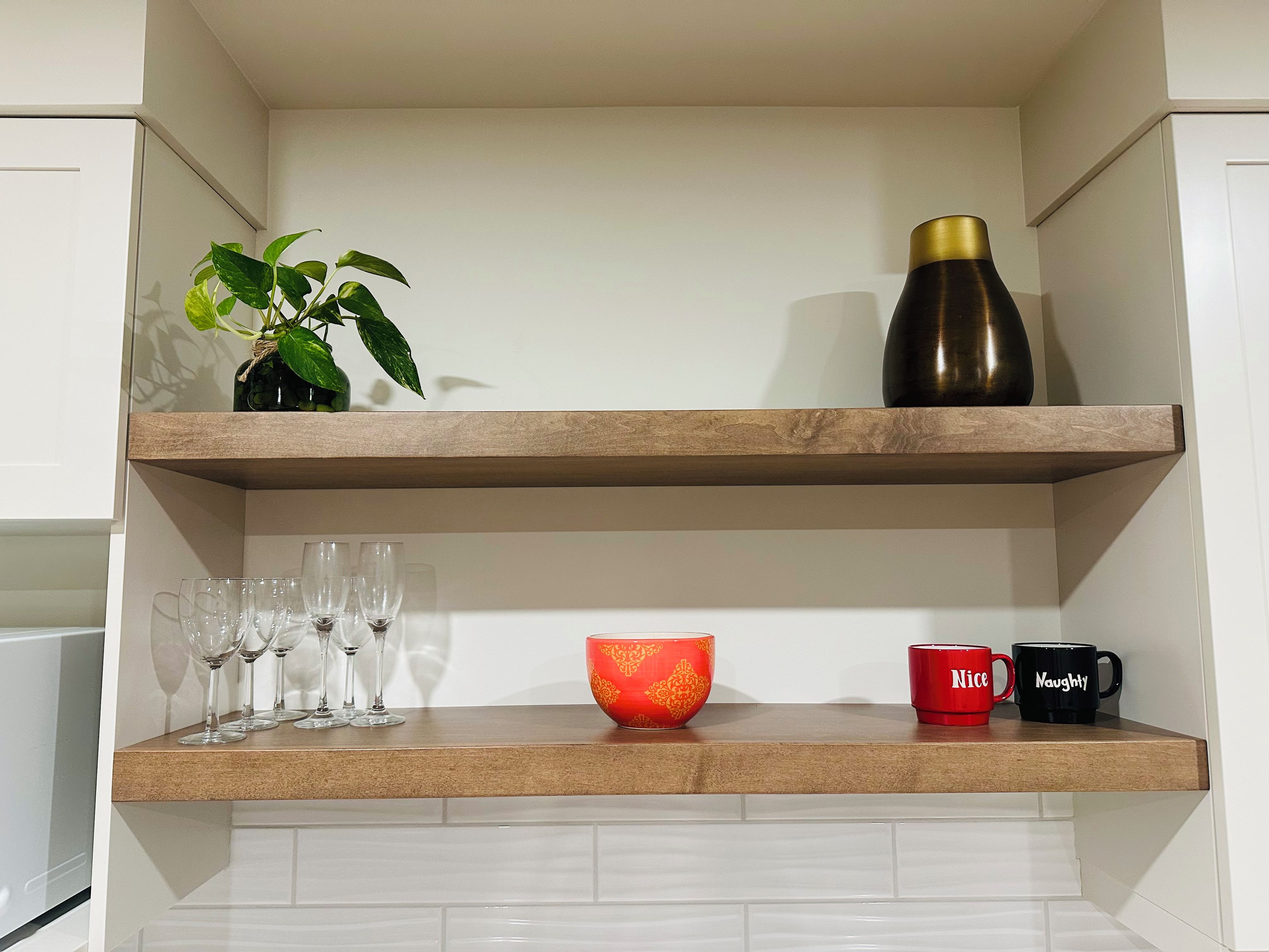Une étagère de cuisine avec une plante en pot, un thermos, un bol décoratif et quelques tasses.