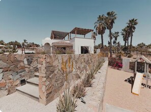 A modern building with a stone facade, a white upper level, and a covered patio area. - Villa with Sauna. Villa Serena (Todos Santos)