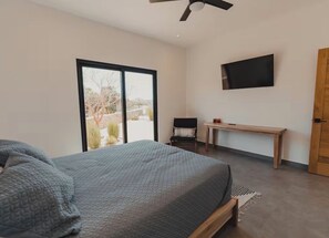 A bedroom with a bed, a desk, a chair, and a television on the wall. - Villa with Sauna. Villa Serena (Todos Santos)