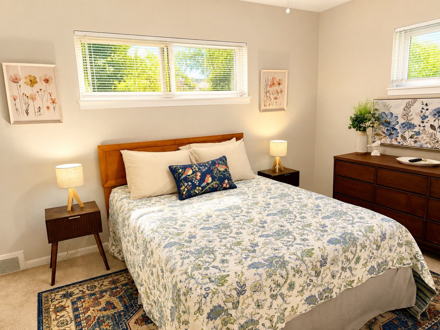 A bedroom with a bed, two bedside tables, a dresser, and a window with blinds.