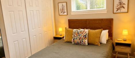 A bedroom with a bed, two bedside tables, a window, and a door.