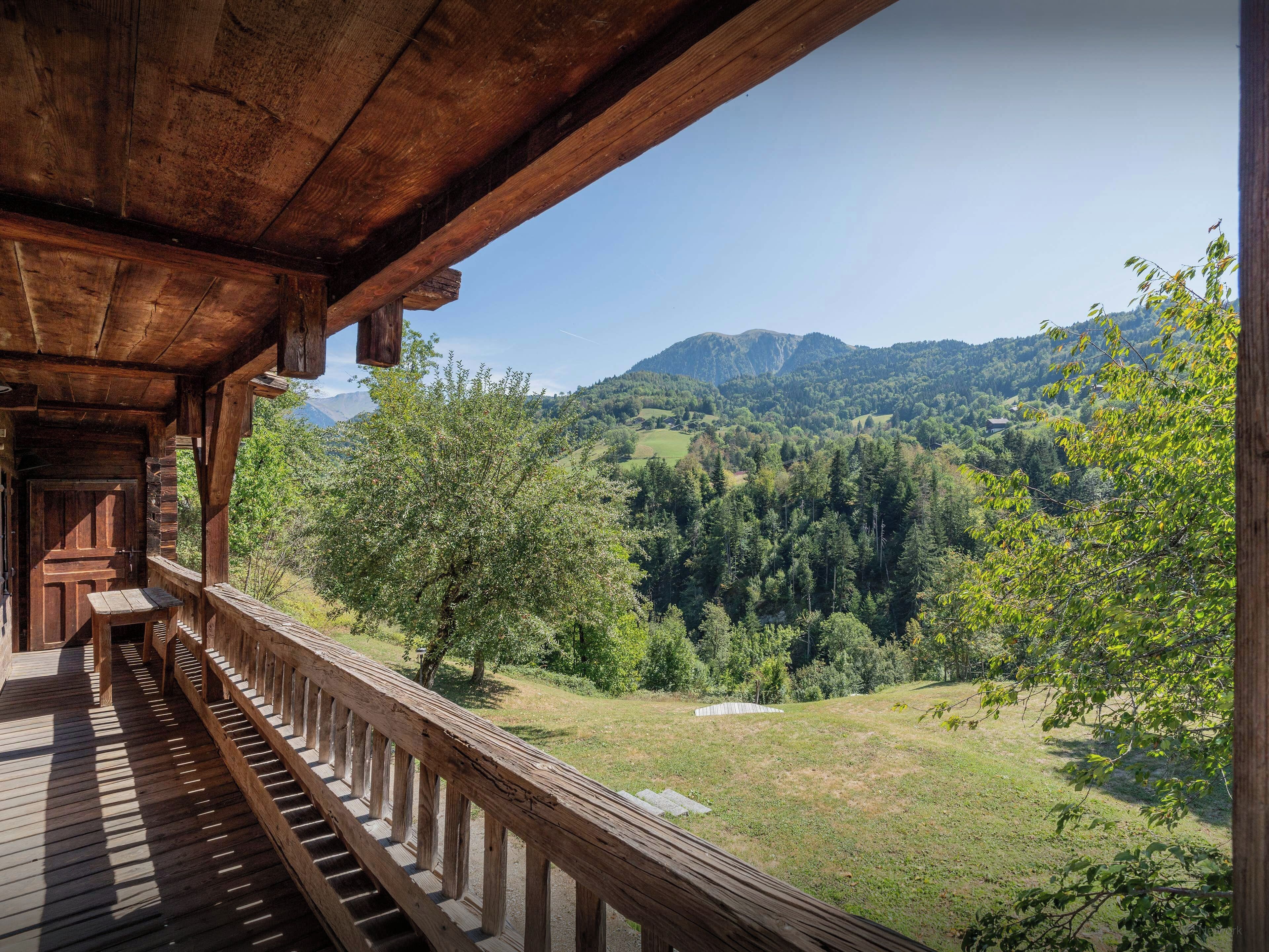 Un balcon en bois offrant une vue sur un paysage montagneux.