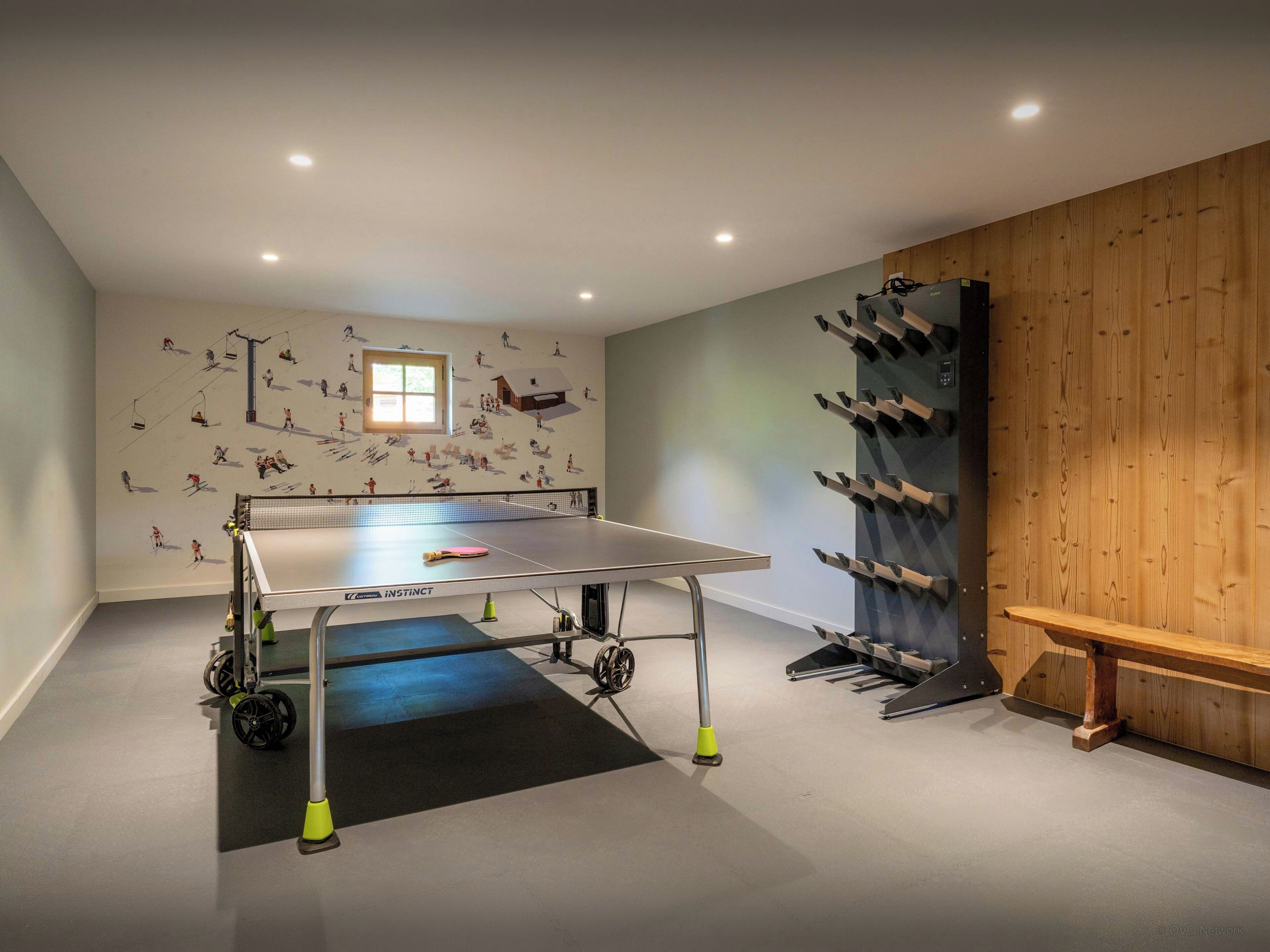 Ein Tischtennis-Tisch in einem Raum mit einer Holzwand und einem Wandgemälde zum Thema Skifahren.