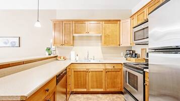 A kitchen with wooden cabinets, a stainless steel refrigerator, and a built-in oven.