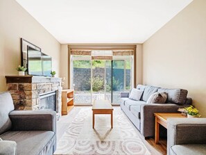 A modern living room with a fireplace, a sofa set, a coffee table, and a television.