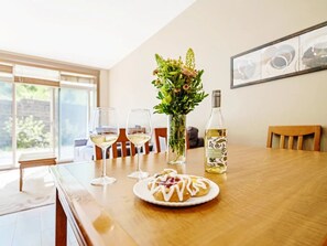 Een eettafel met een bord eten, wijnglazen, een fles witte wijn en een vaas bloemen.
