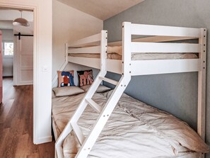 Ein Stockbett mit einer Leiter, einem Fenster und einer Tür zu einem anderen Raum.