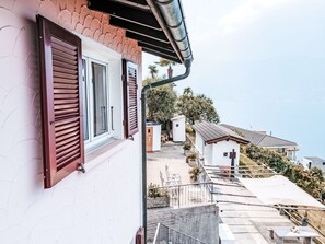 Ein Wohngebäude mit Balkon, einer Treppe, die zu einer unteren Ebene führt, und freiem Blick auf die umliegende Nachbarschaft.