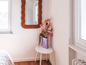 A room with a white wall, a round white table with a purple vase, and a mirror with a wavy frame. - Casa Martini by Interhome (Vairano)