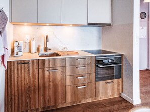 Eine moderne Küche mit Holzschränken, einem eingebauten Backofen und einer Kaffeemaschine.